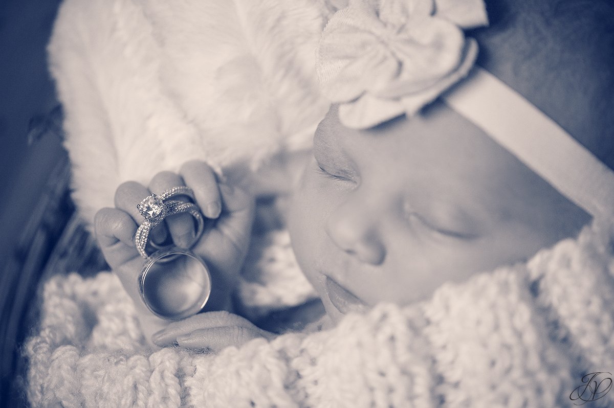 newborn holding parent's wedding rings
