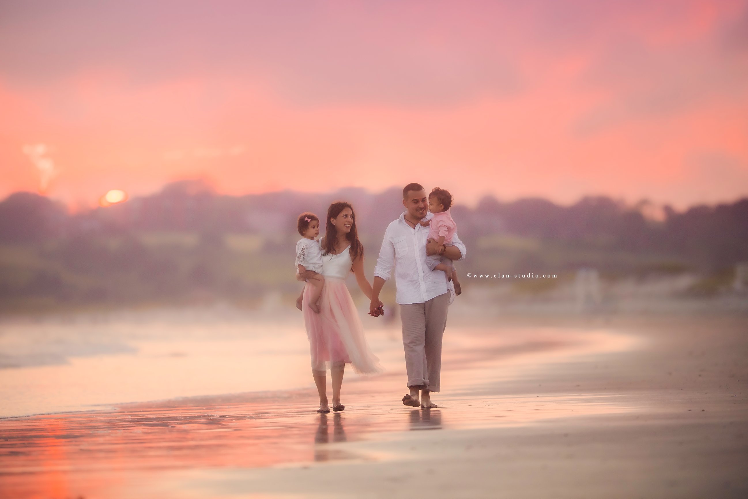 dreamy pink hued image of family walking on beach at sunset, by Elan Studio