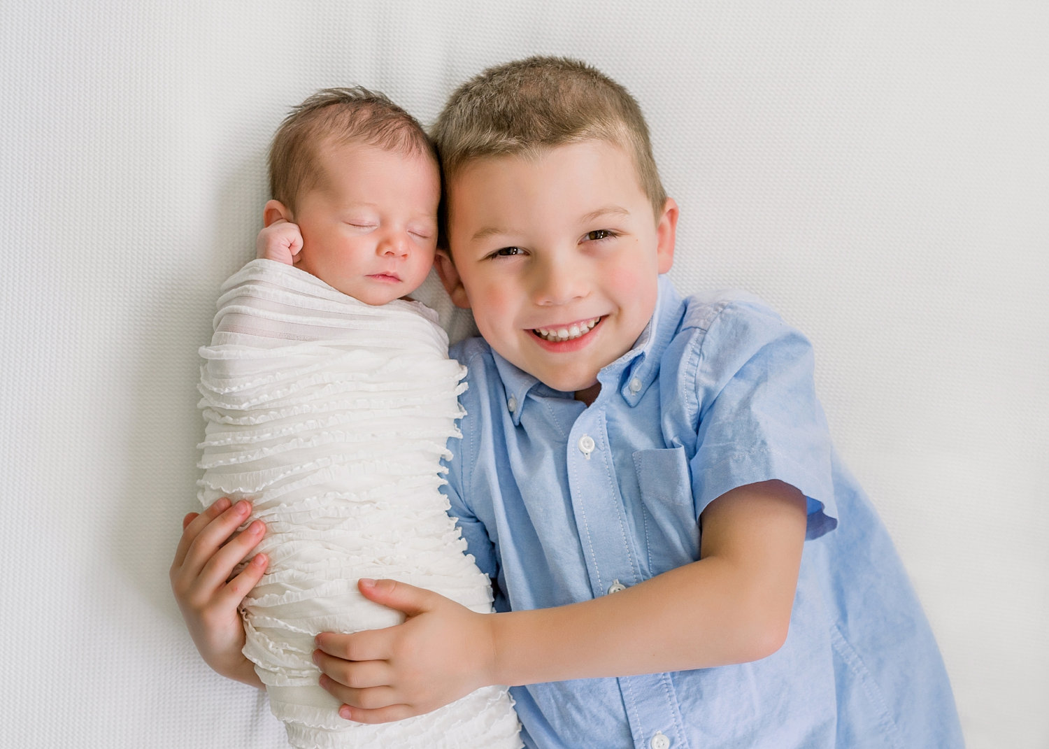 smiling big brother holding newborn sibling, in-home newborn photography, Rya Duncklee