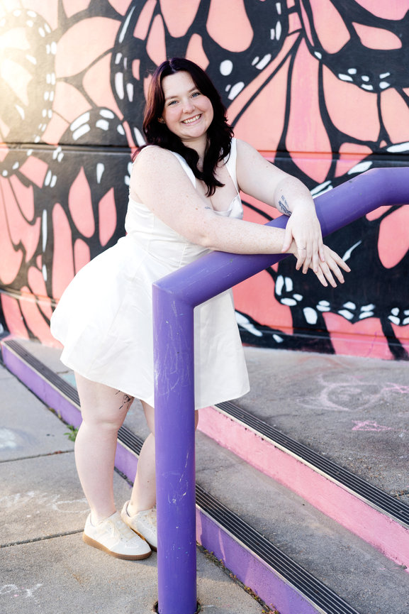 Woman in a white dress leaning on a purple railing
