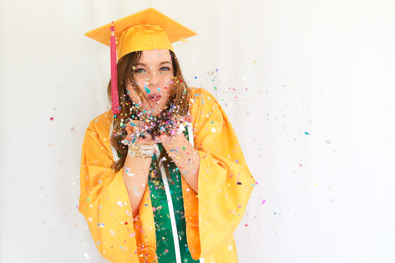 Colorado State University graduate blowing confetti while wearing cap and gown. Captured to celebrate achievement, joy, and legacy. Luxury graduation portrait experience for discerning Colorado families and university graduates.