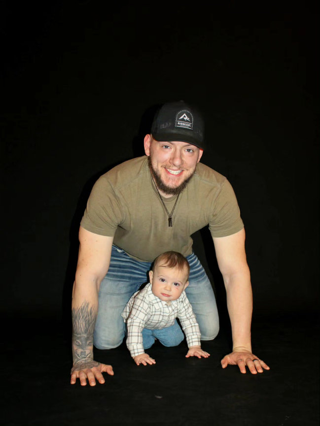 Man and baby posing on a dark studio backdrop