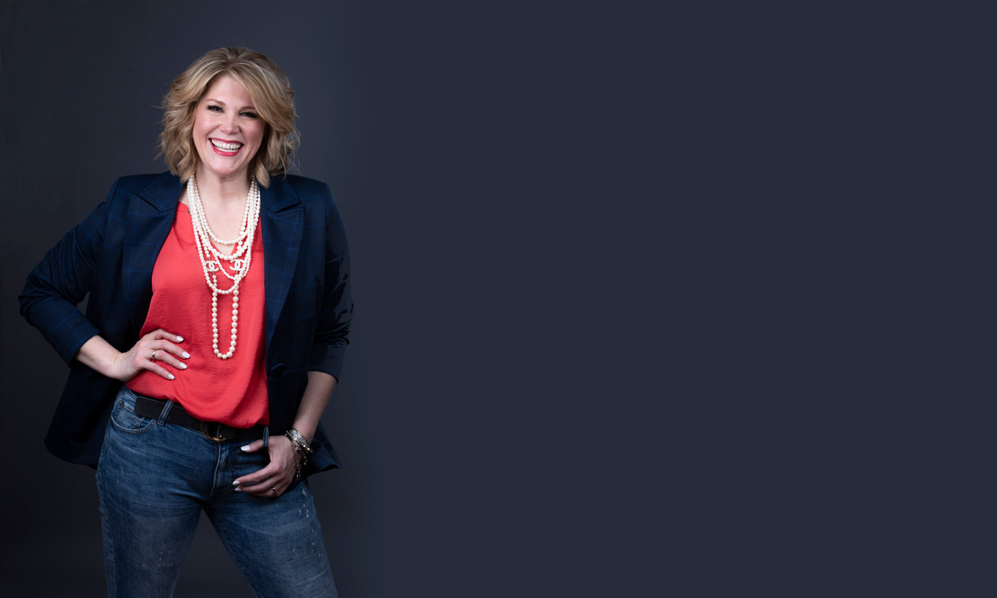 fashionable happy woman wearing jeans, orange top, jacket and multiple strands of pearls