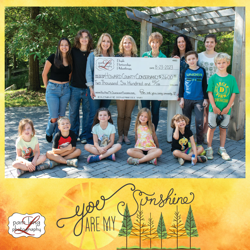 Group of kids and adults holding a large check as a donation