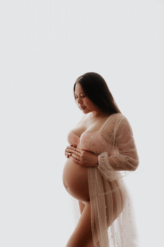 pregnant mother holding her belly looking down in a sexy lace top and bottom