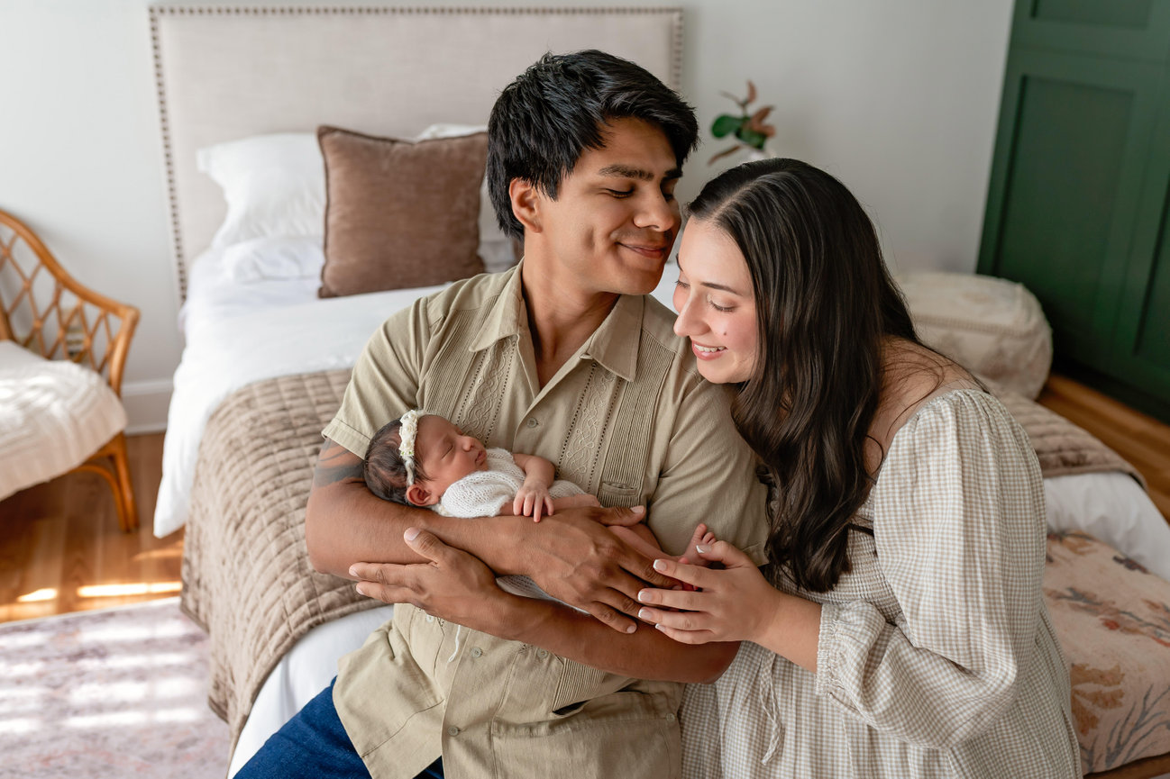 New parents lovingly holding their sleeping newborn in a cozy bedroom