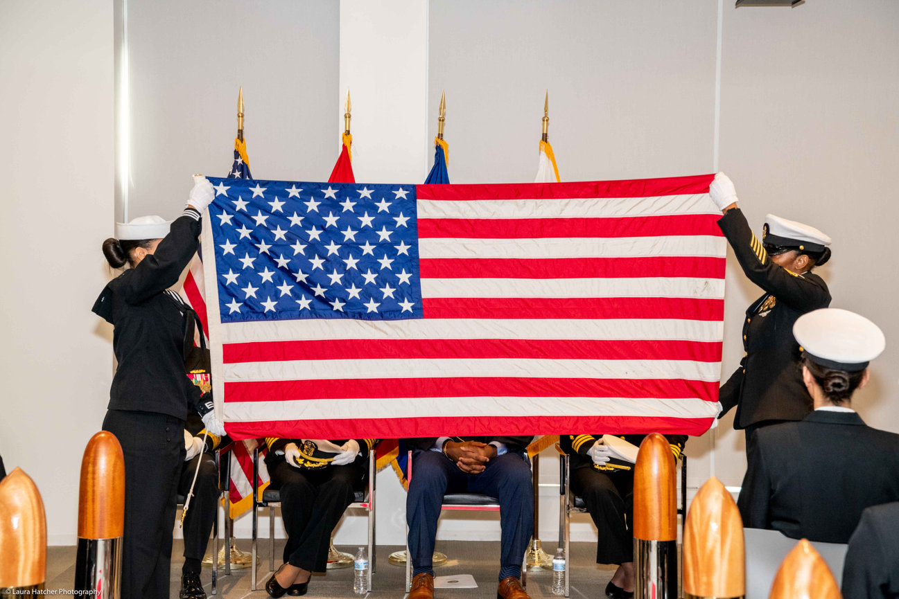 Navy Sailors stretching out the American flag during a flag folding ceremony