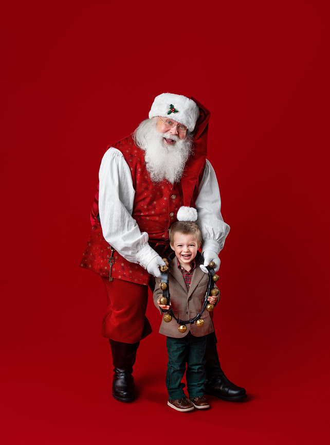 Santa and boy against a classic red backdrop during a Christmas mini session in Wooster, Ohio
