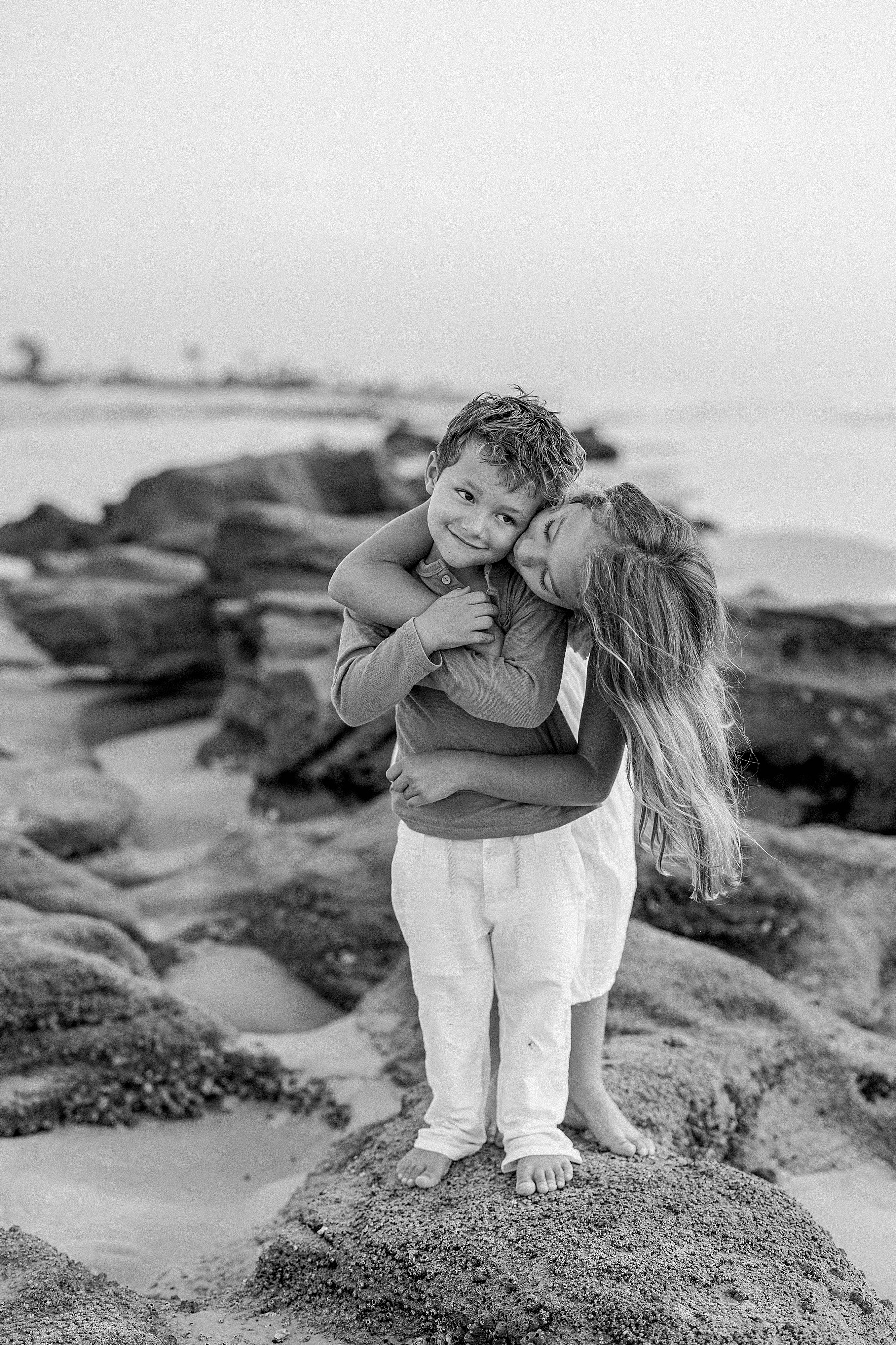 kids kissing on the beach in black and white
