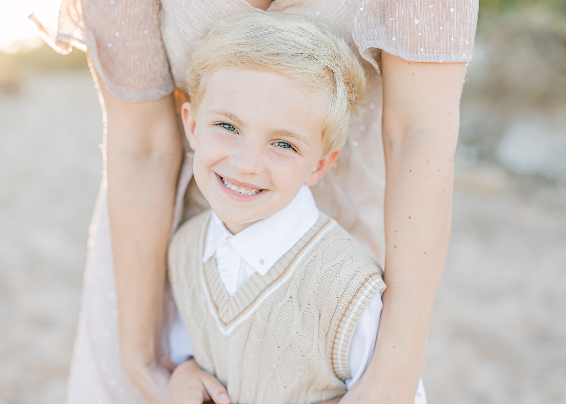 little blond haired boy smiling with a neutral vest on the beach at sunset in saint augustine florida