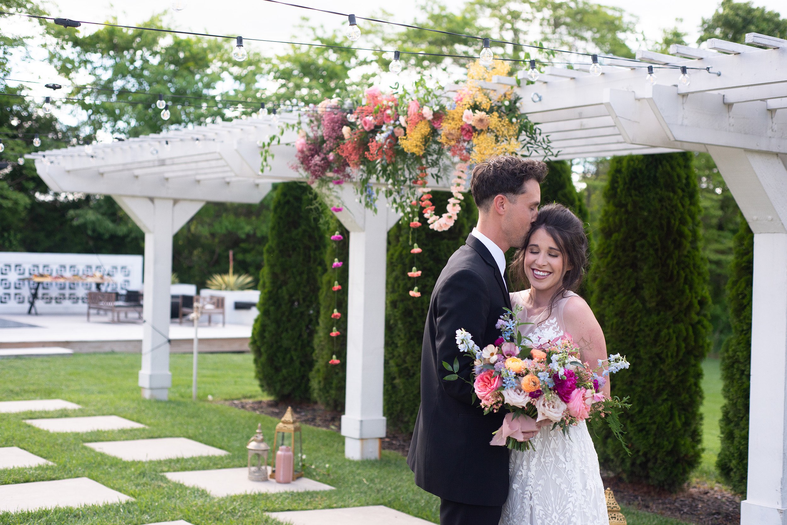 Bride holding colorful bouquet standing with groom at Greenhouse Two Rivers.