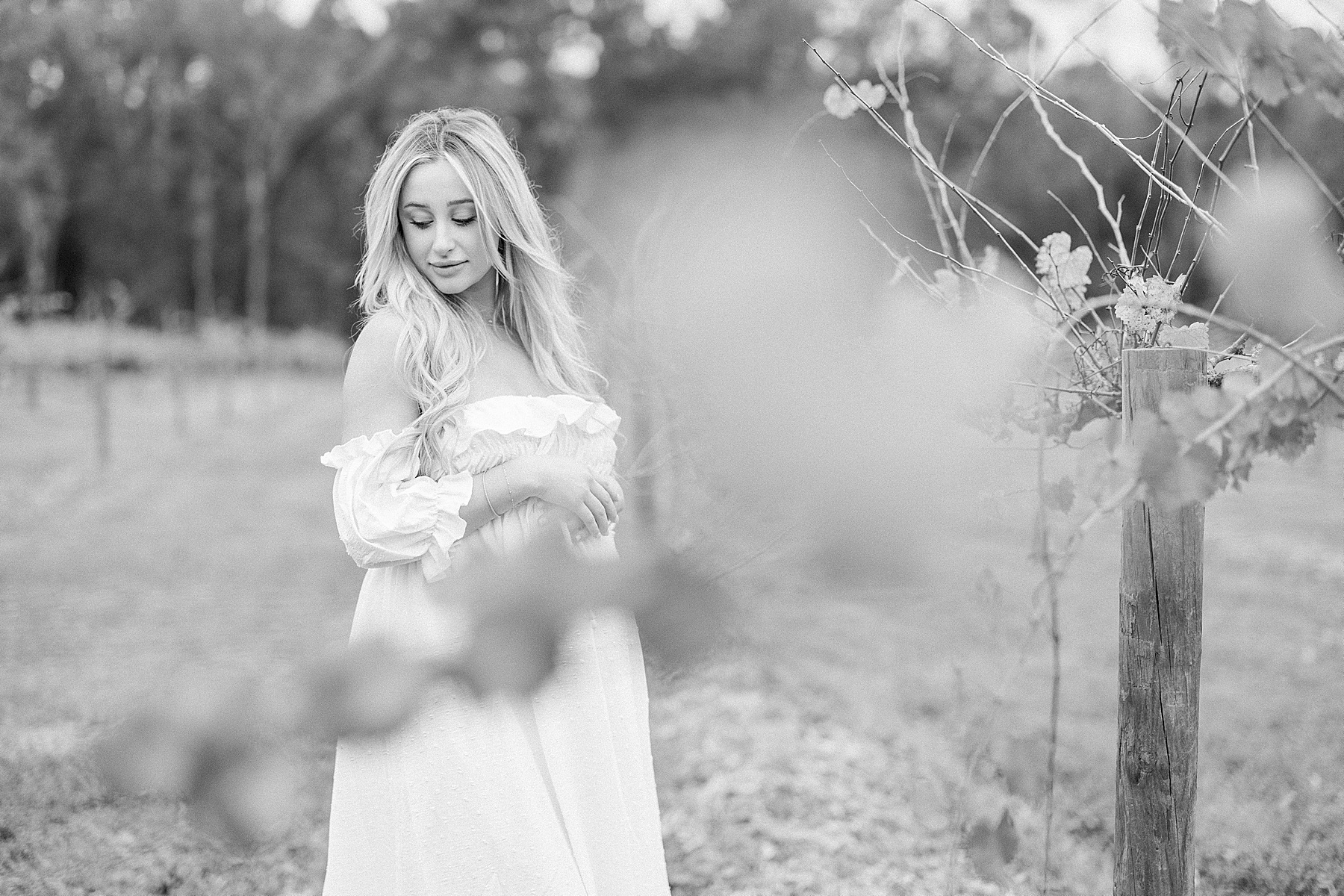 black and white maternity portrait of blonde woman standing in the vineyards at Congaree and Penn Farm Jacksonville Florida