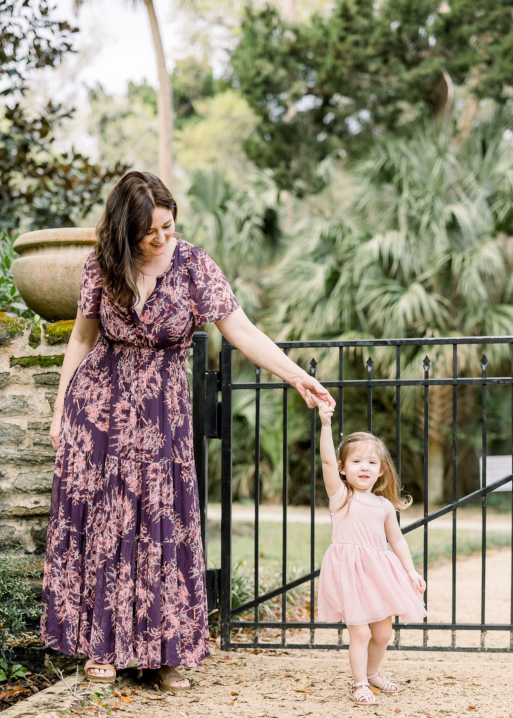 woman in purple floral maxi dress dancing with little girl in pink tutu dress in the spring in the park