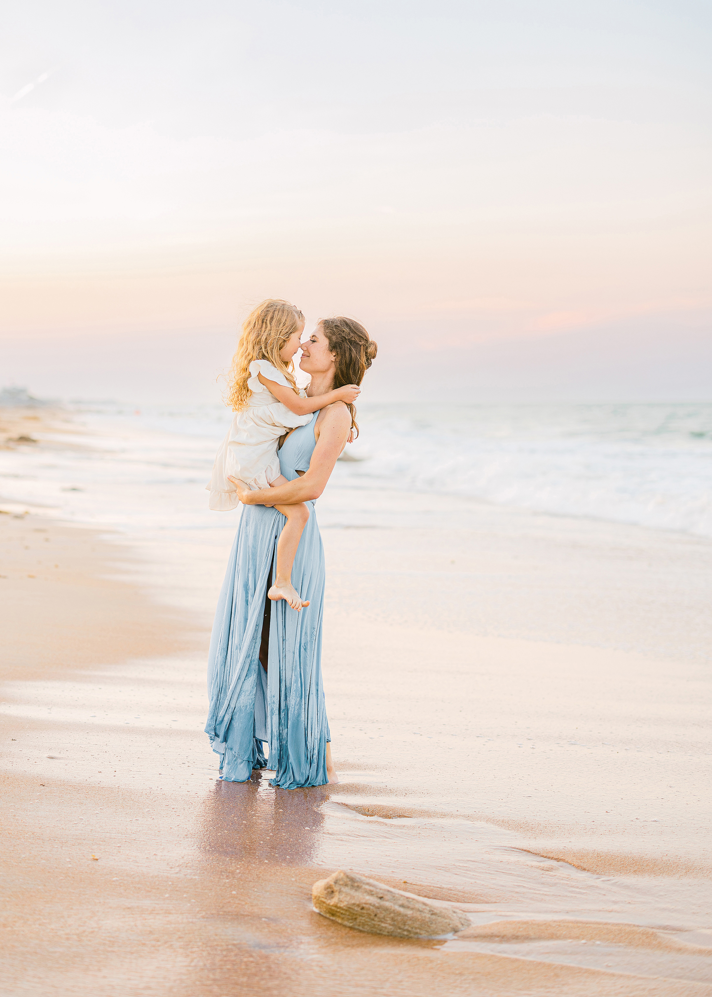 woman holding little girl on St. Augustine beach at sunset 
