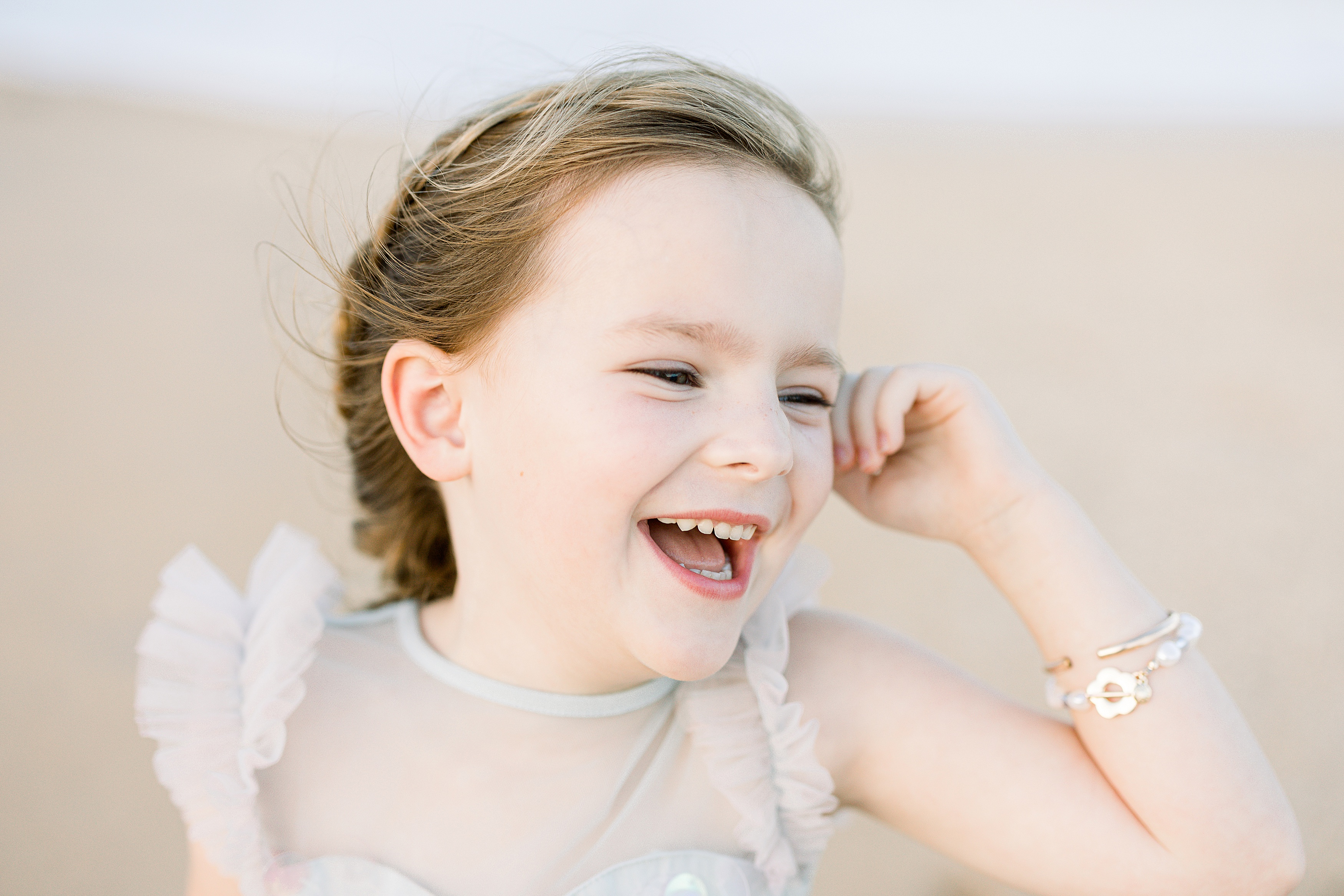 little girl laughing away from the camera wearing a pearl bracelet