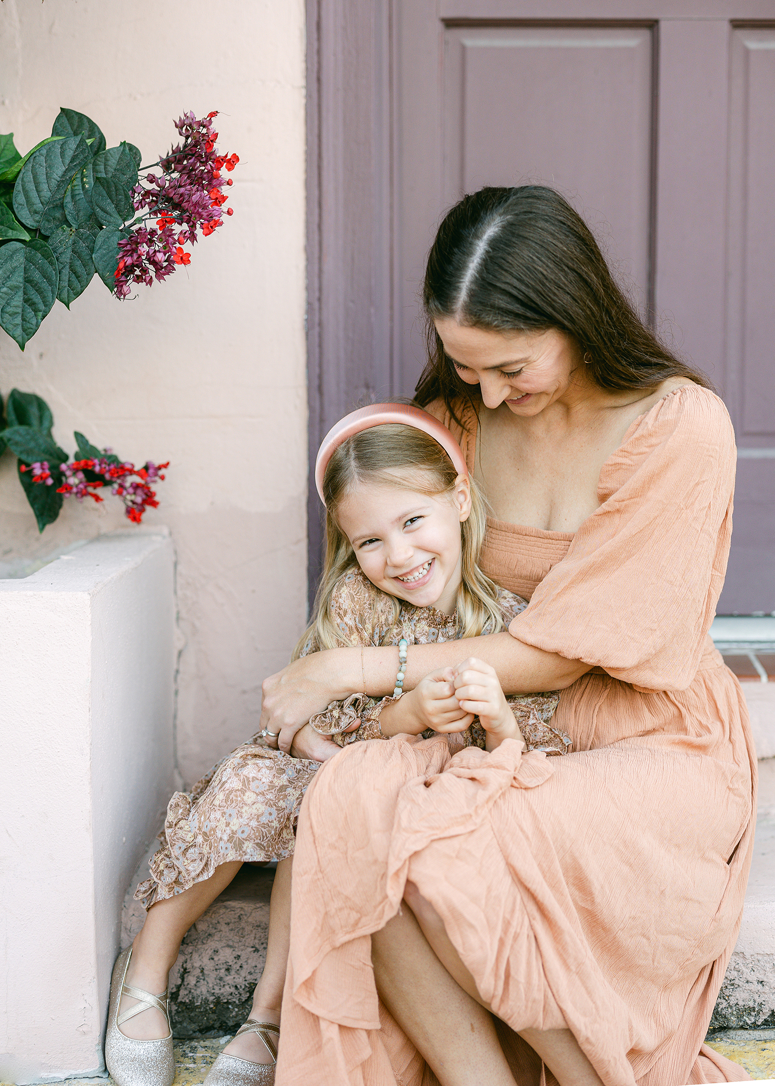 Close up portrait of mother and daughter laughing together on the steps downtown.