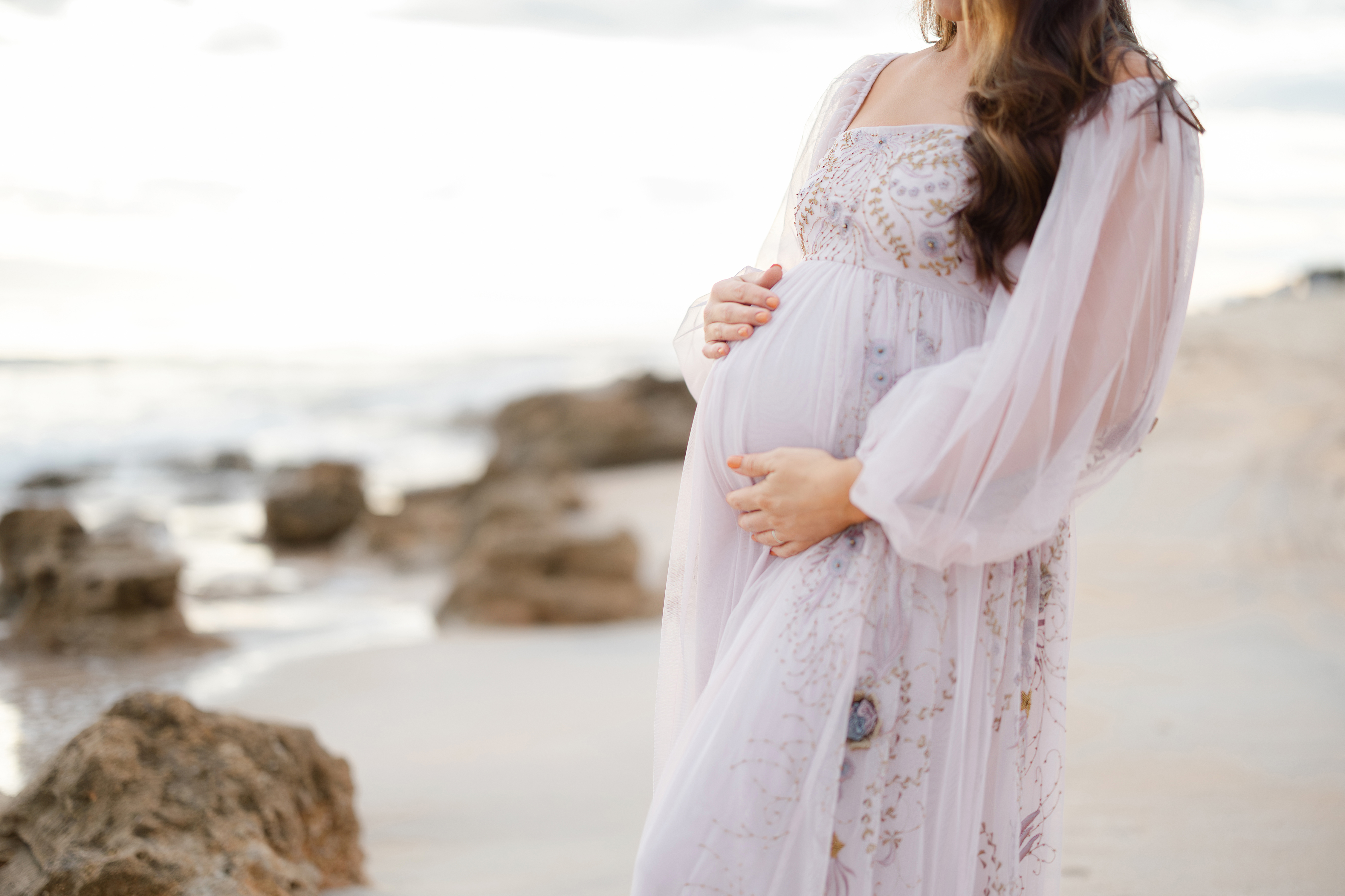 Airy sunrise maternity portrait of a woman in a pale purple tulle dress with sequin.