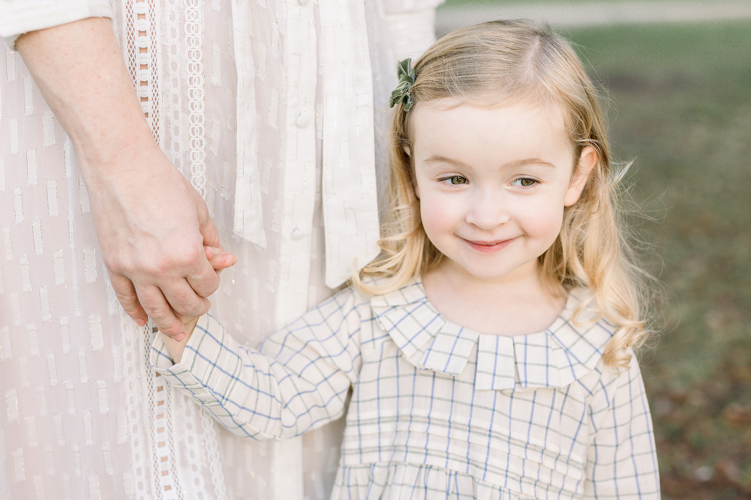 A fall portrait of a little girl in a vintage dress holding her Moms hand.