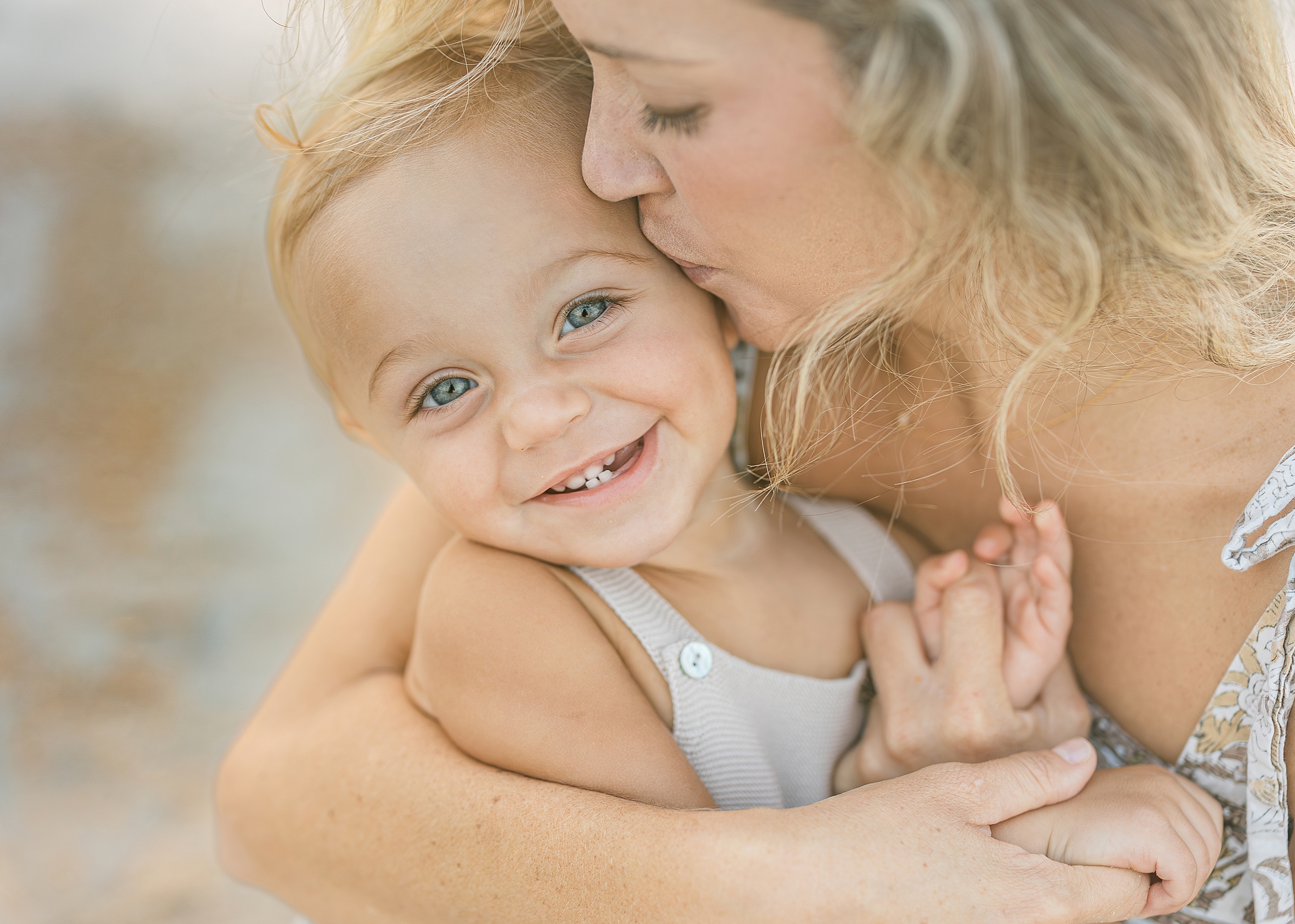 A close up portrait of a baby boy with his mother, laughing.