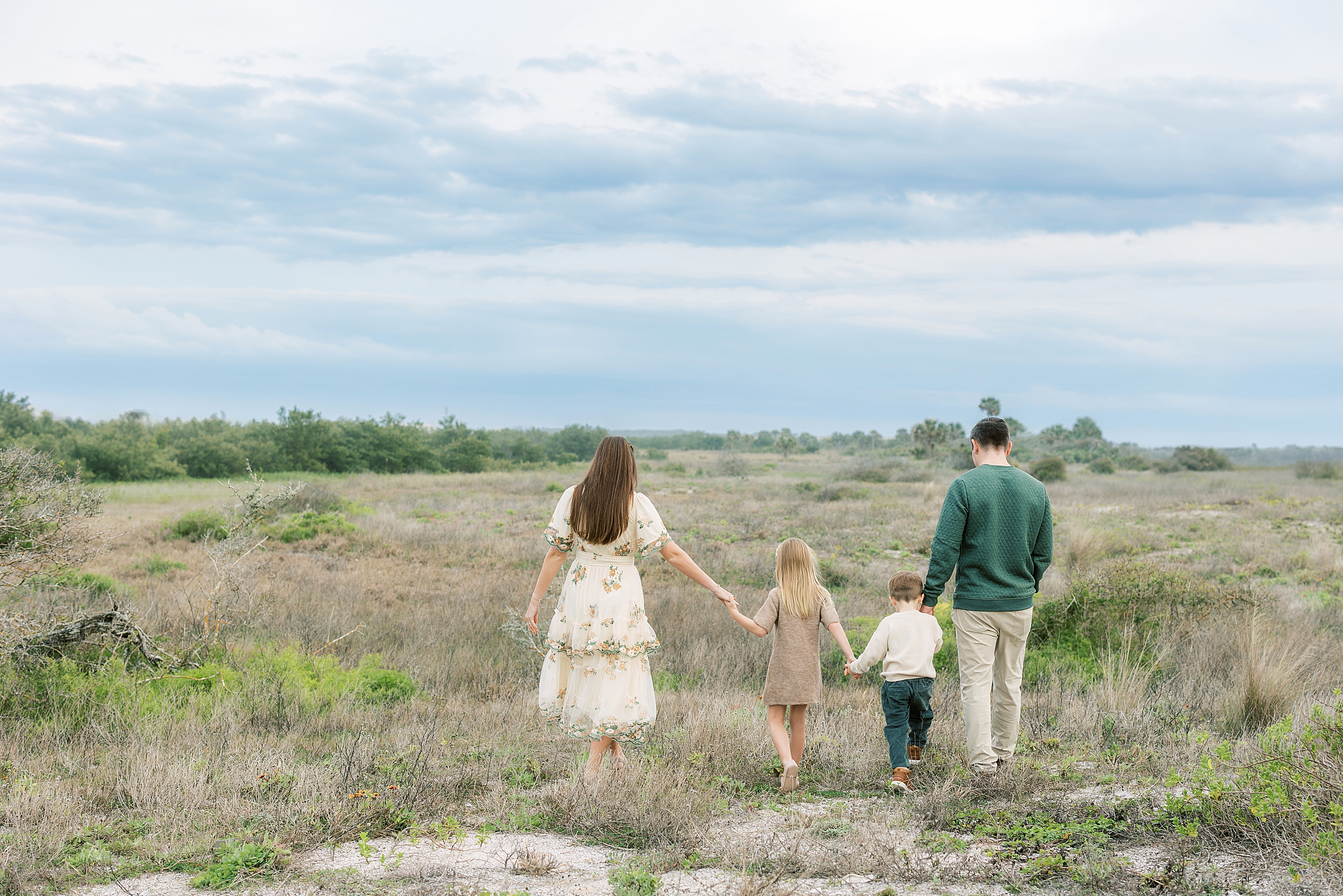 A family dressed in earthy neutrals walks together in the dunes along St. Augustine Beach.