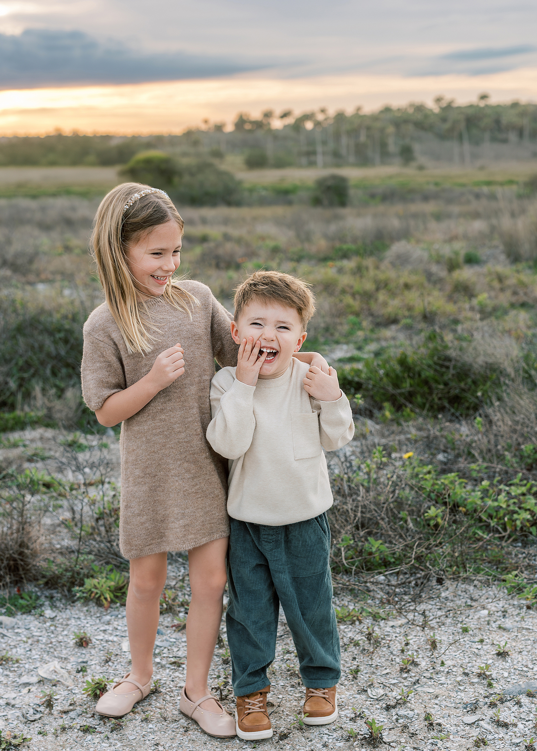 A childhood sibling portrait of two little kids laughing with each other.