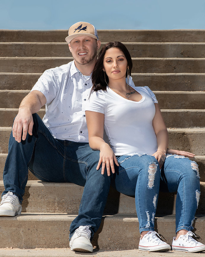 Older couple sitting on outdoor steps, smiling at the camera.