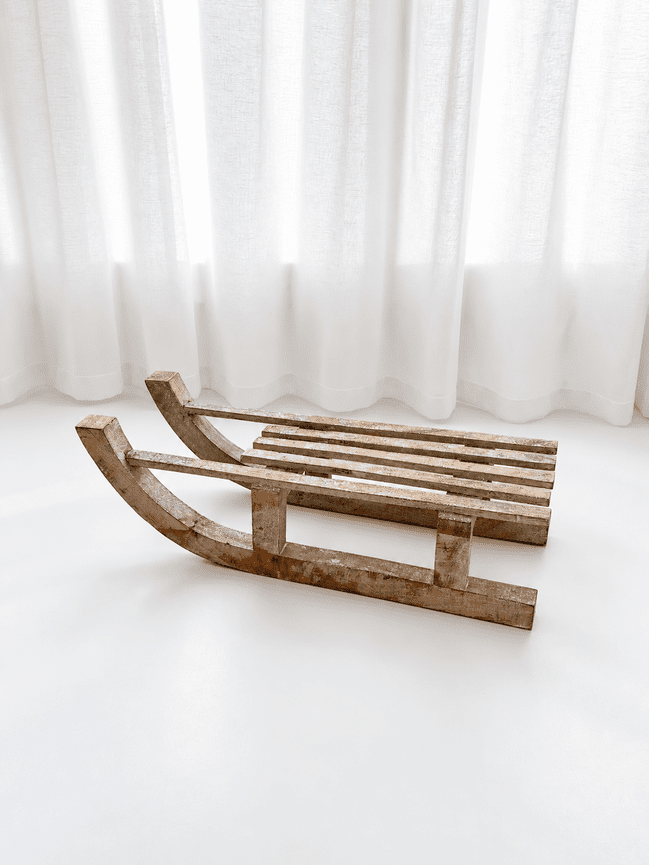 Wooden sleigh with silver sparkle on white flooring