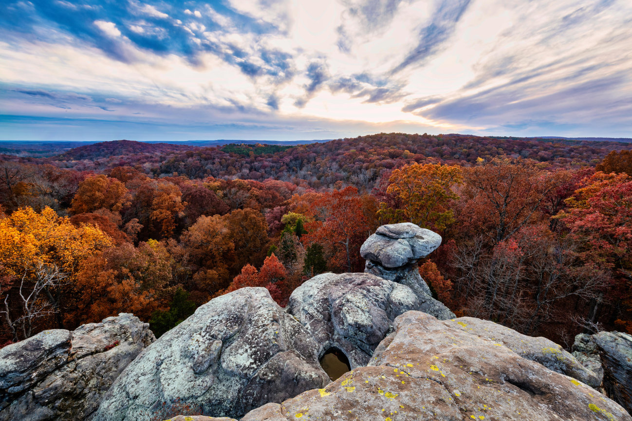 Autumn forest landscape from rocky overlook at sunset with colorful trees and dramatic cloudy sky