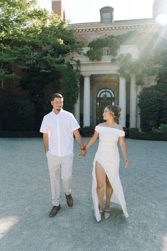 Couple walking hand in hand in front of estate
