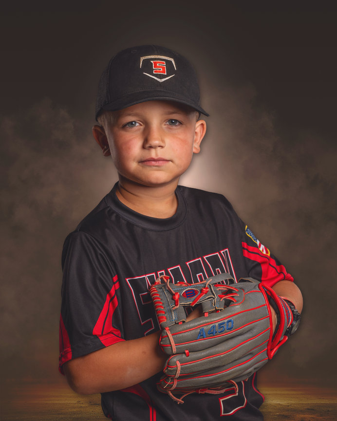 Young baseball player in black and red uniform holding a glove in a studio portrait