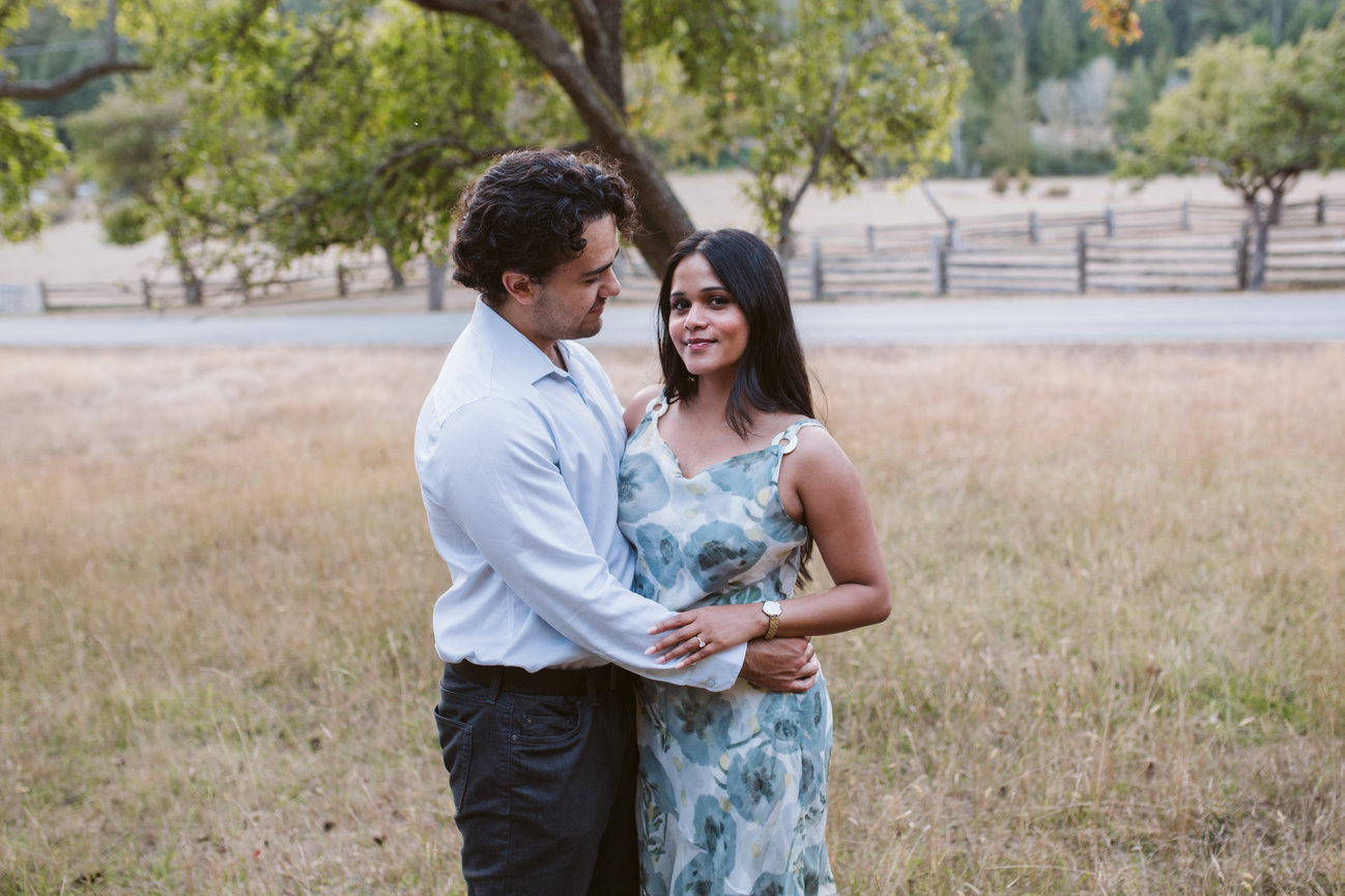 Engaged couple sharing a quiet moment in a grassy orchard