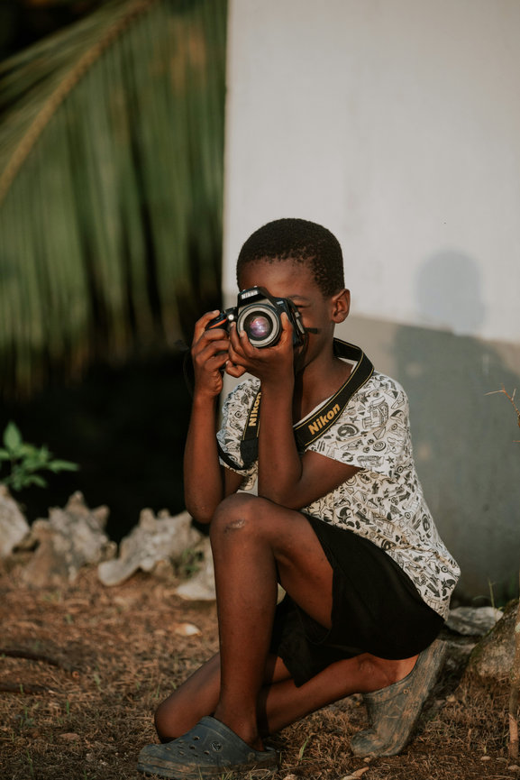Child sitting and holding camera