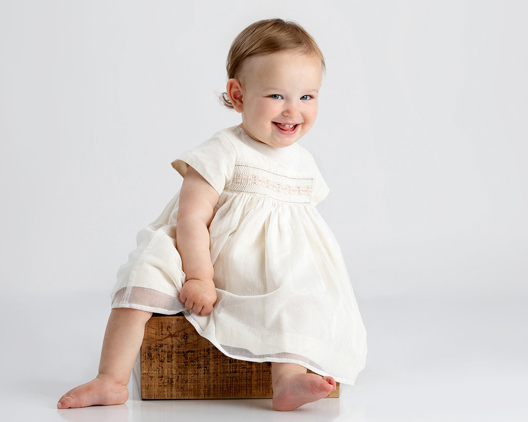 Laughing toddler sitting on a small box