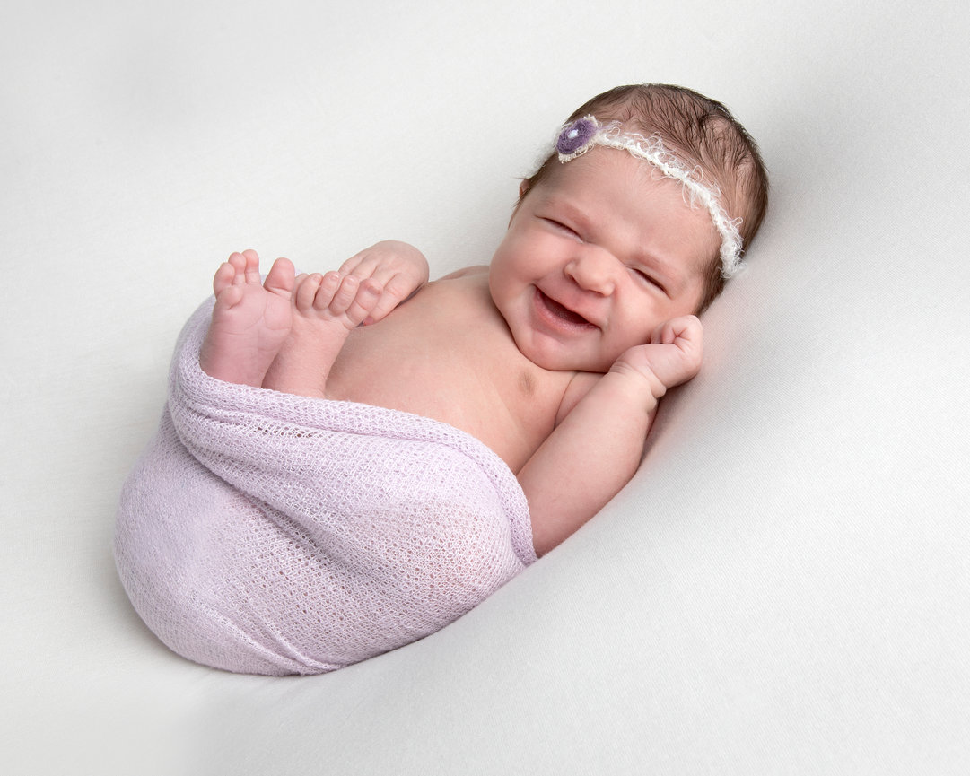 Smiling newborn wrapped in a purple blanket