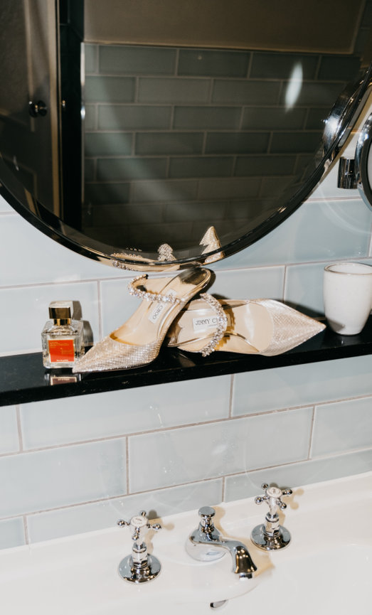 High-fashion wedding details at King Street Townhouse featuring Jimmy Choo shoes and bridal fragrance in a cinematic flash style.