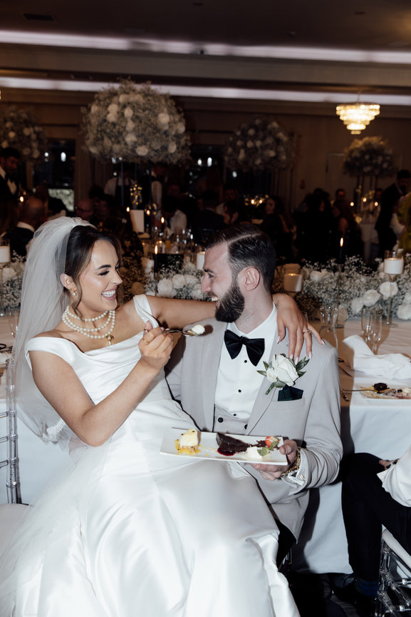 A relaxed, editorial wedding portrait of a a bride playfully feeding cake to the groom at Merrydale Manor reception in Cheshire.