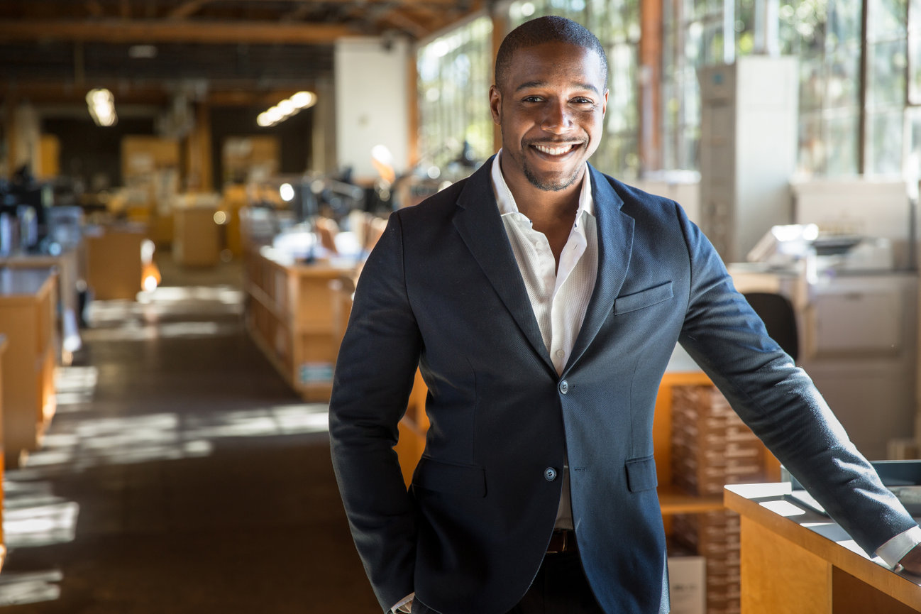 Business portrait of a man in a navy suit standing in a restaurant.