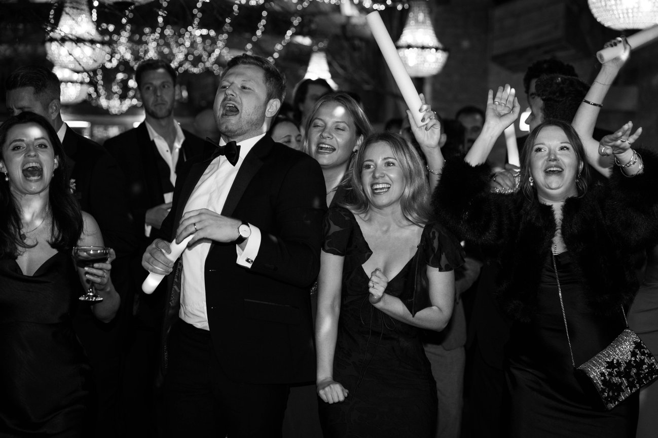 Monochrome flash photography at Hampton Court; a candid, high-energy shot of wedding guests on a crowded dance floor.