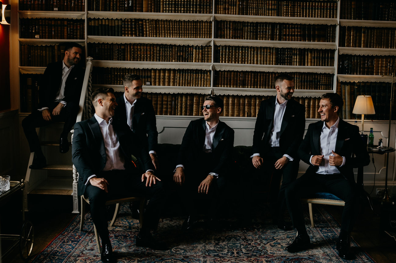 Dark and moody wedding photography at Iscoyd Park. A group of groomsmen pose together inside the venue's historic library.