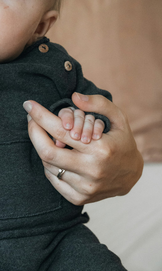 Adult gently holding a newborn baby's hand