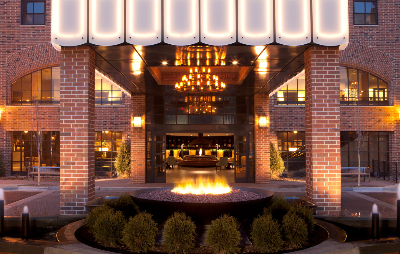 Beautifully designed Architecture of a Porte Cochere downtown Minnesota with Warm fireplace in center and chandeliers leading you to inside Lobby area.