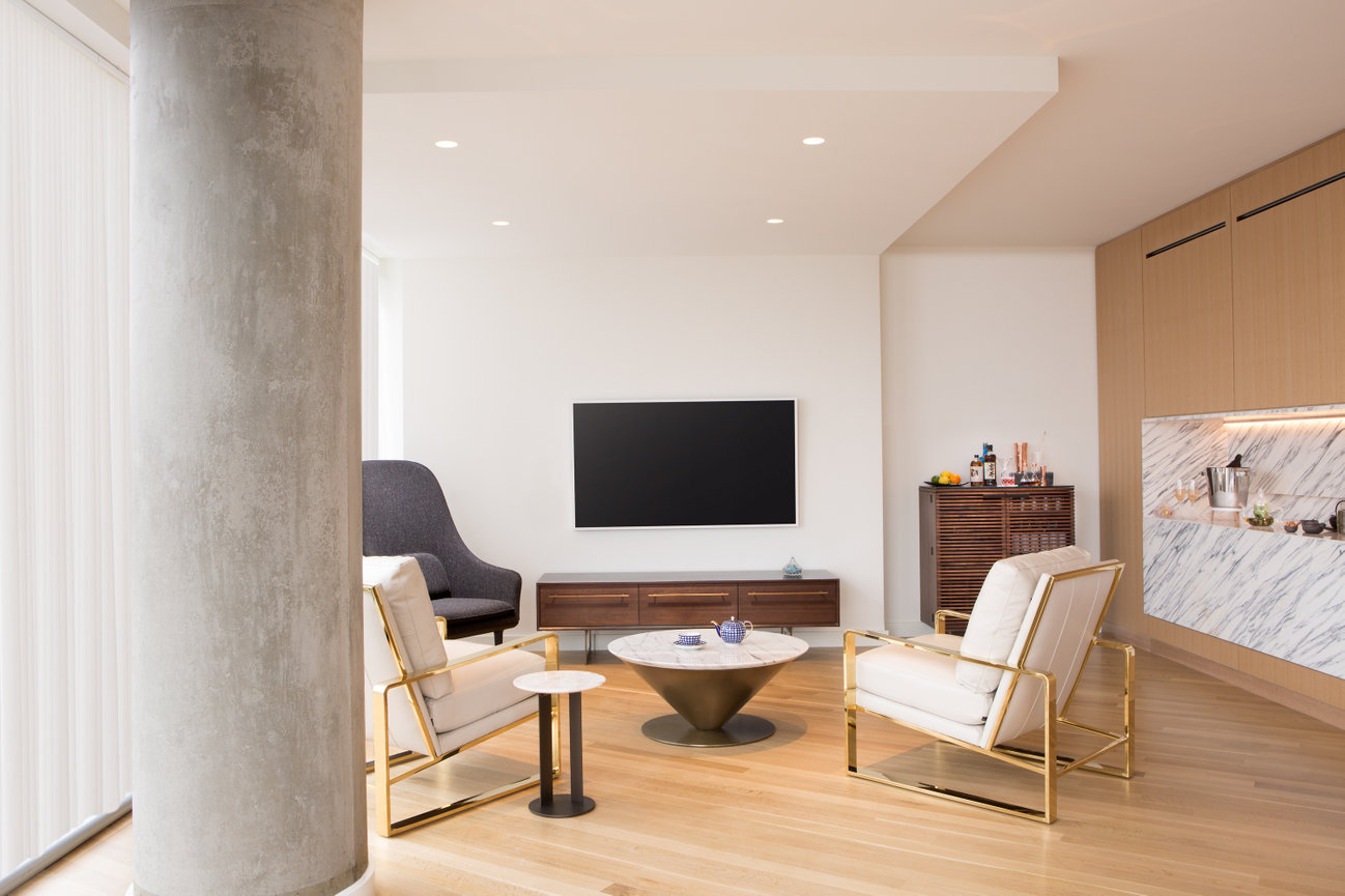 Conrad DC Private Lounge designed in all white with natural concrete columns with natural wood floors and setup for a private event.