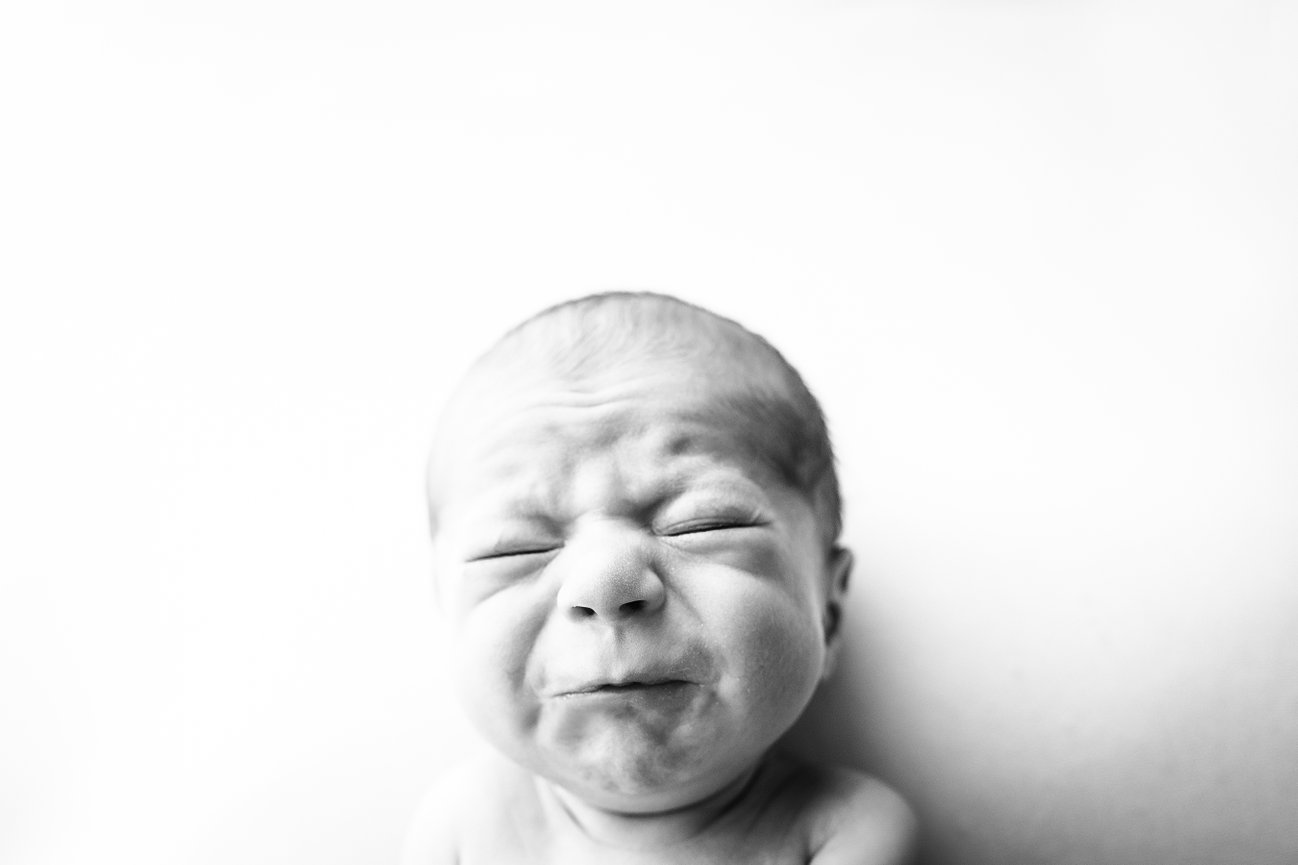 One-week-old newborn captured mid-yawn in black and white, blending artful photography with natural expression