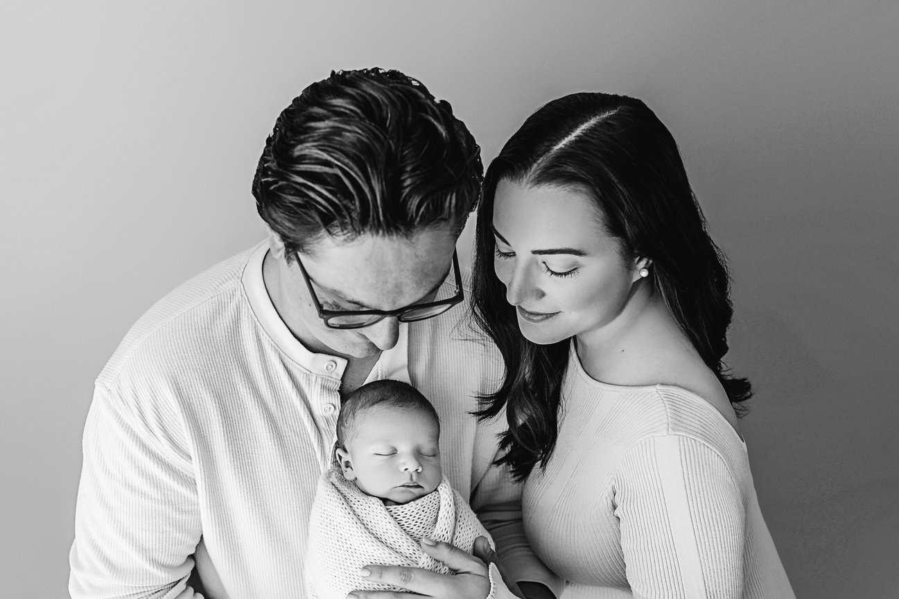 Emotional newborn photo with mom and dad cradling baby close during timeless studio session in Manasquan, NJ
