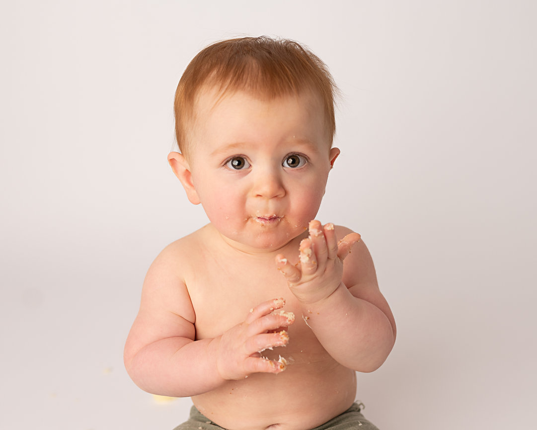 After the smash—baby laughing with frosting on face