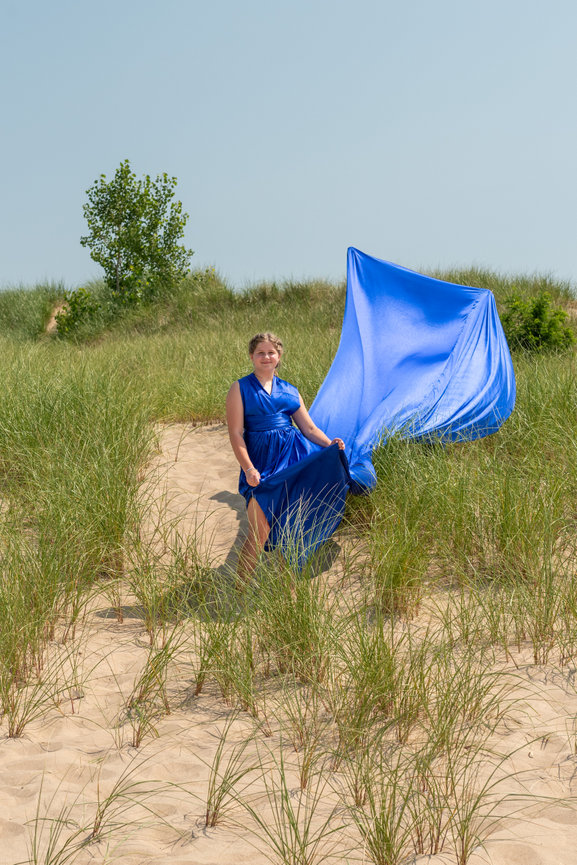 Woman in a blue dress standing among sand dunes