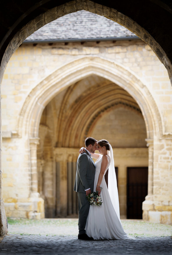 Bride and groom embracing in the historic courtyard of Maison du Prieuré in Romainmôtier, Switzerland
