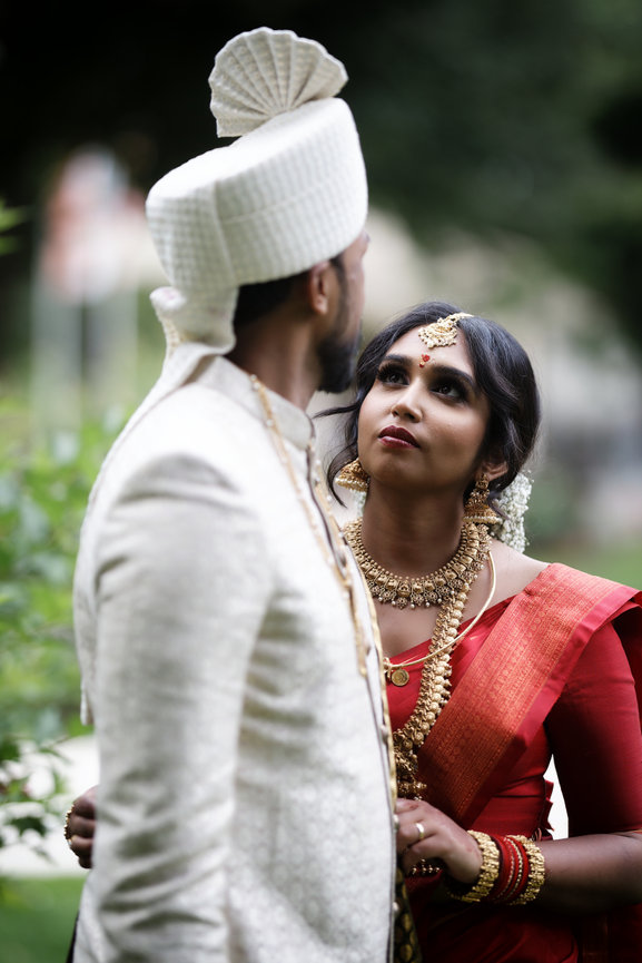 Bride in a red sari looking at the groom during an outdoor wedding at Kempinski Palace Engelberg, Switzerland