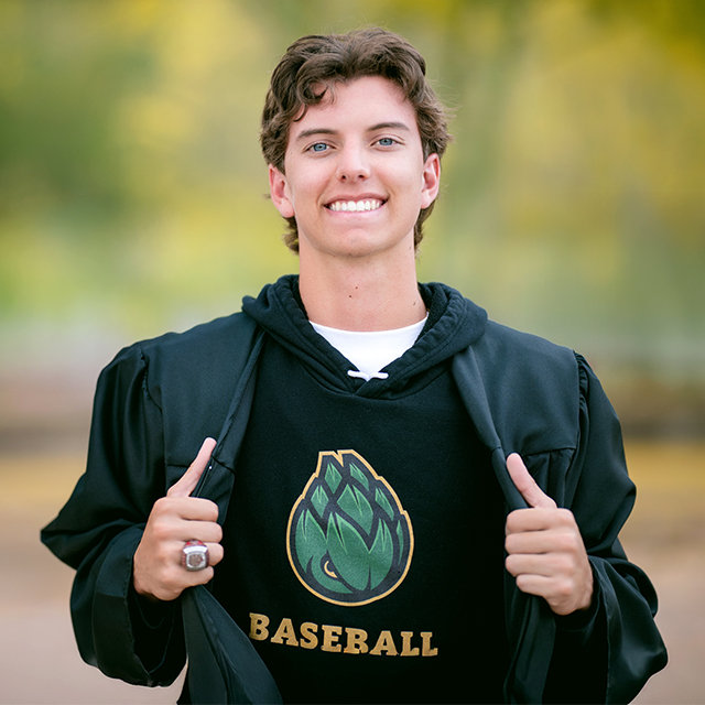 Senior boy wearing baseball sweatshirt and smiling at camera