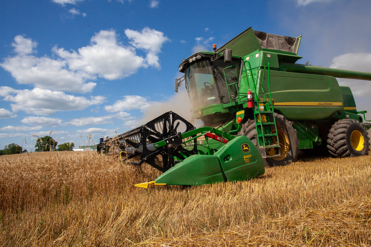 A combine harvesting a field of wheat. The harvest in full motion